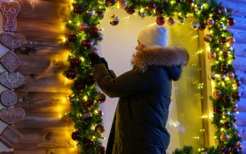 Frau dekoriert ein Verkaufsfenster weihnachtlich