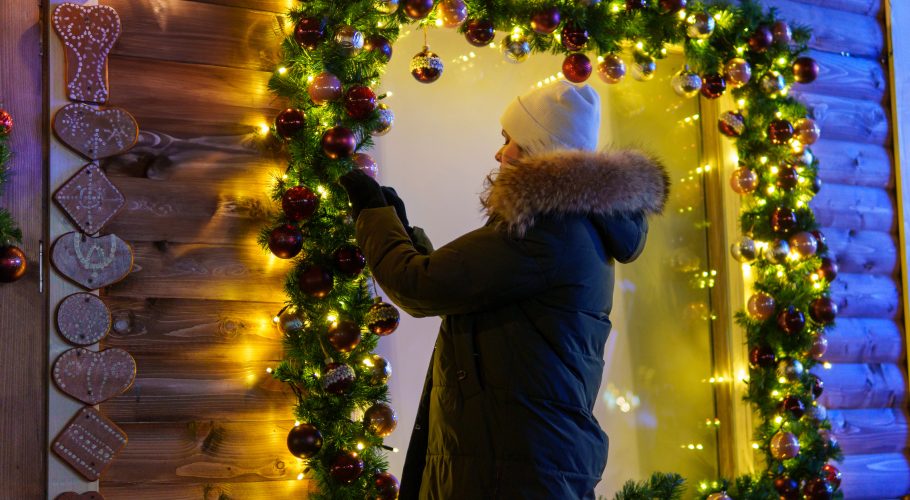 Frau dekoriert ein Verkaufsfenster weihnachtlich